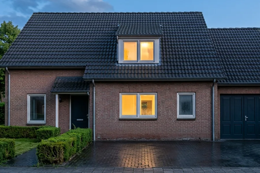 Woonhuis in de schemering na de reiniging, het dak egaal antraciet en de oprit nat